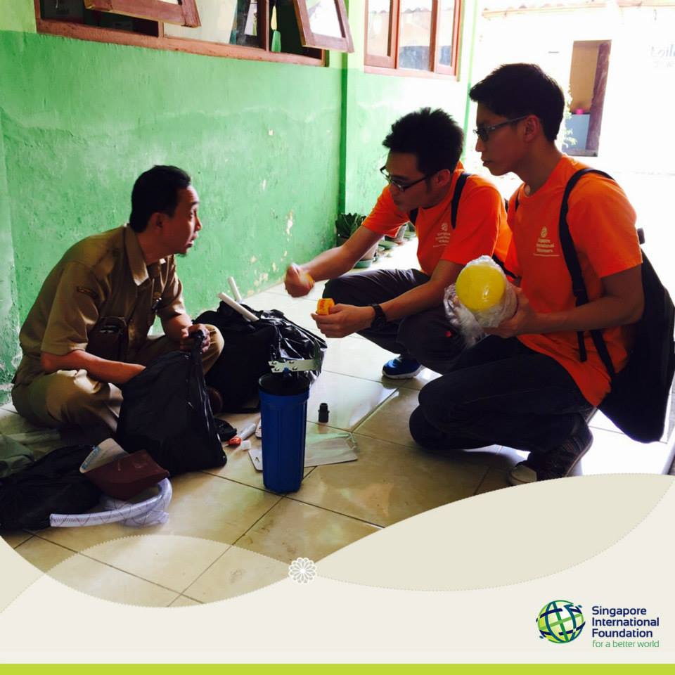 SIVs Chia Wei Choon and Chan Yong Chien explaining how the membrane water filter system works to a staff member of Host Agency, Cipta Karya Public Works Service.