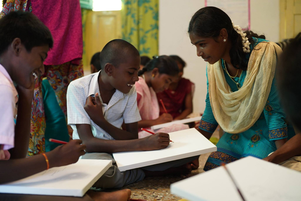 Workshop participant of “Empowering Communities through Arts Education” programme (right) working with the local community affected by HIV during a portrait painting session.