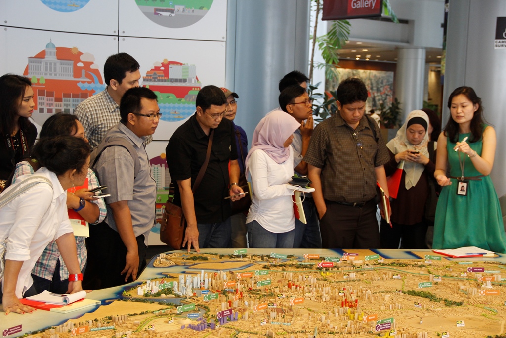A staff member from the Urban Redevelopment Agency (URA) explaining how the URA plans land use in Singapore, illustrating with a scale model of the city at the Singapore City Gallery. 