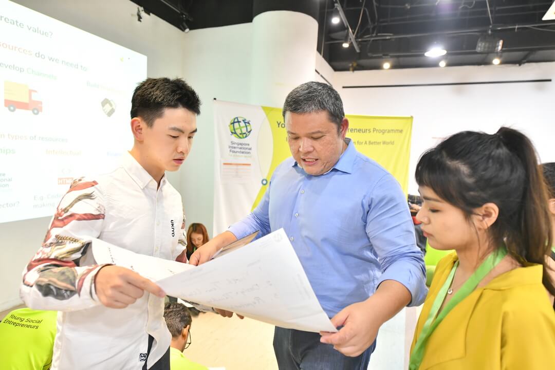 Russ Neu, Founder and CEO of Social Collider from Singapore works with team Peach Talk (China) at a Social Enterprise Marketplace where YSEs learnt ways to leverage shared resources to advance the growth of their SEs. 