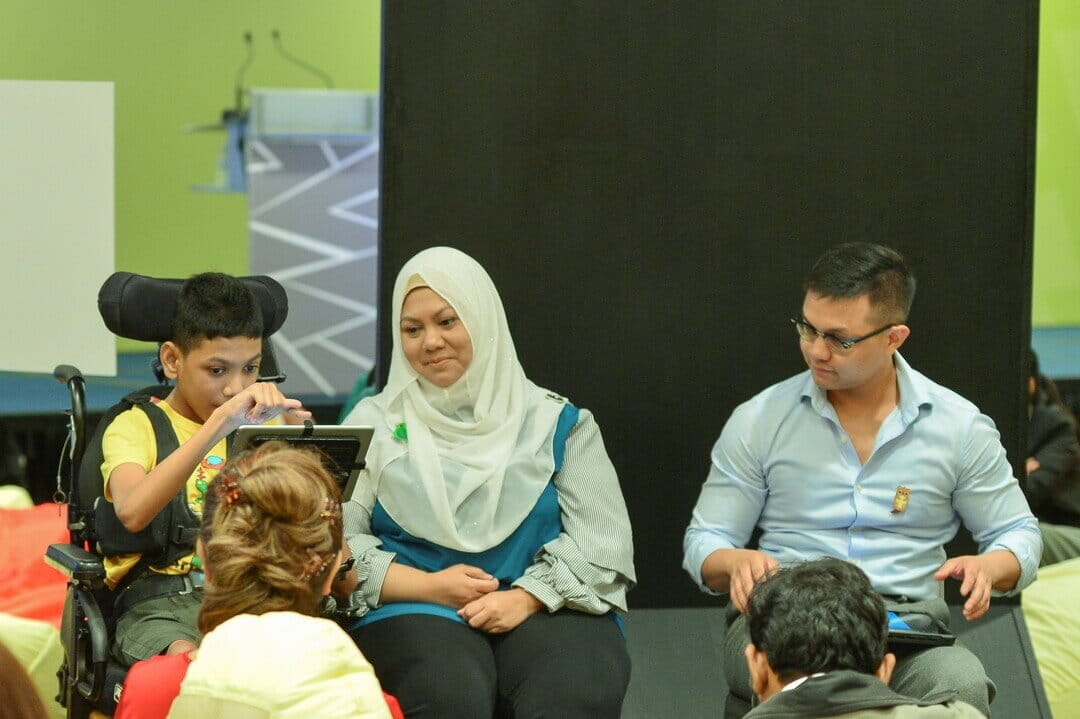 'Human Library' and YSE 2018 alumnus Aminur Rasyid (right) from Junior Art Lab describes his experience training Muhammad Sayfullah (left), who has quadriplegic cerebral palsy, in digital art design. Tapping on assistive technology, Sayfullah is empowered to produce artwork. He shares how he hopes to support his mother (centre) and family through the sale of his work. 