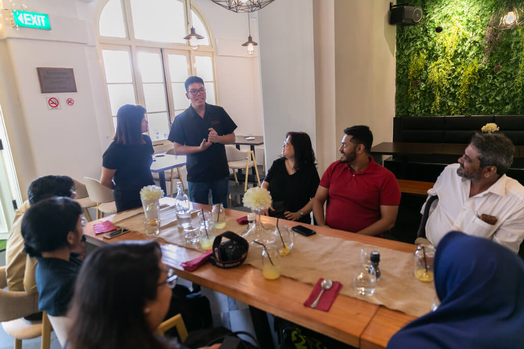 Timothy Lee (standing, right), a service staff with autism, describing how working in social enterprise restaurant, Tribe, has given him independence and empowered him. 
