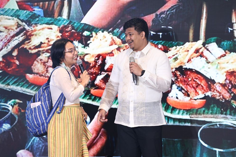 Lara Jean Lupenario Salaysay (left) shares the rich culture and flavours of the Philippines during the AYF 2025 Cultural Night.
