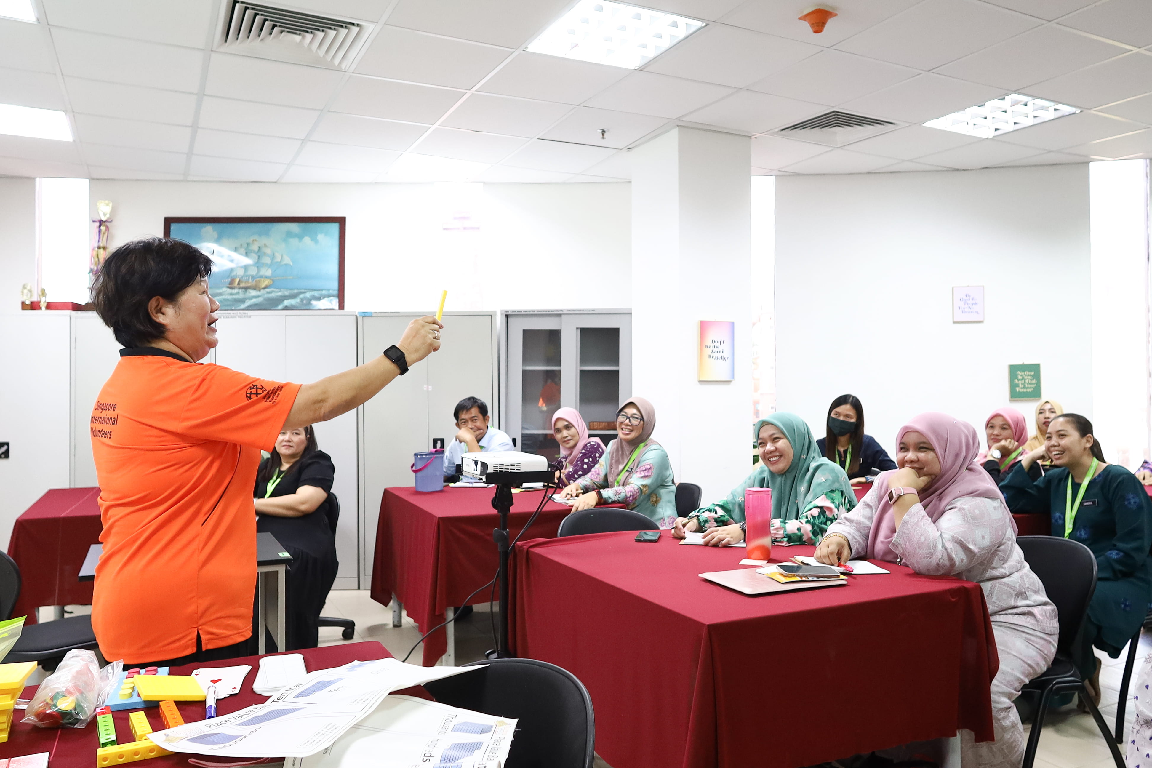 SIV Ms Juliana Donna Loh (in orange) demonstrating the use of Base Ten Blocks, an educational tool that helps students to visualise numbers, at the first Maths PLUS workshop.