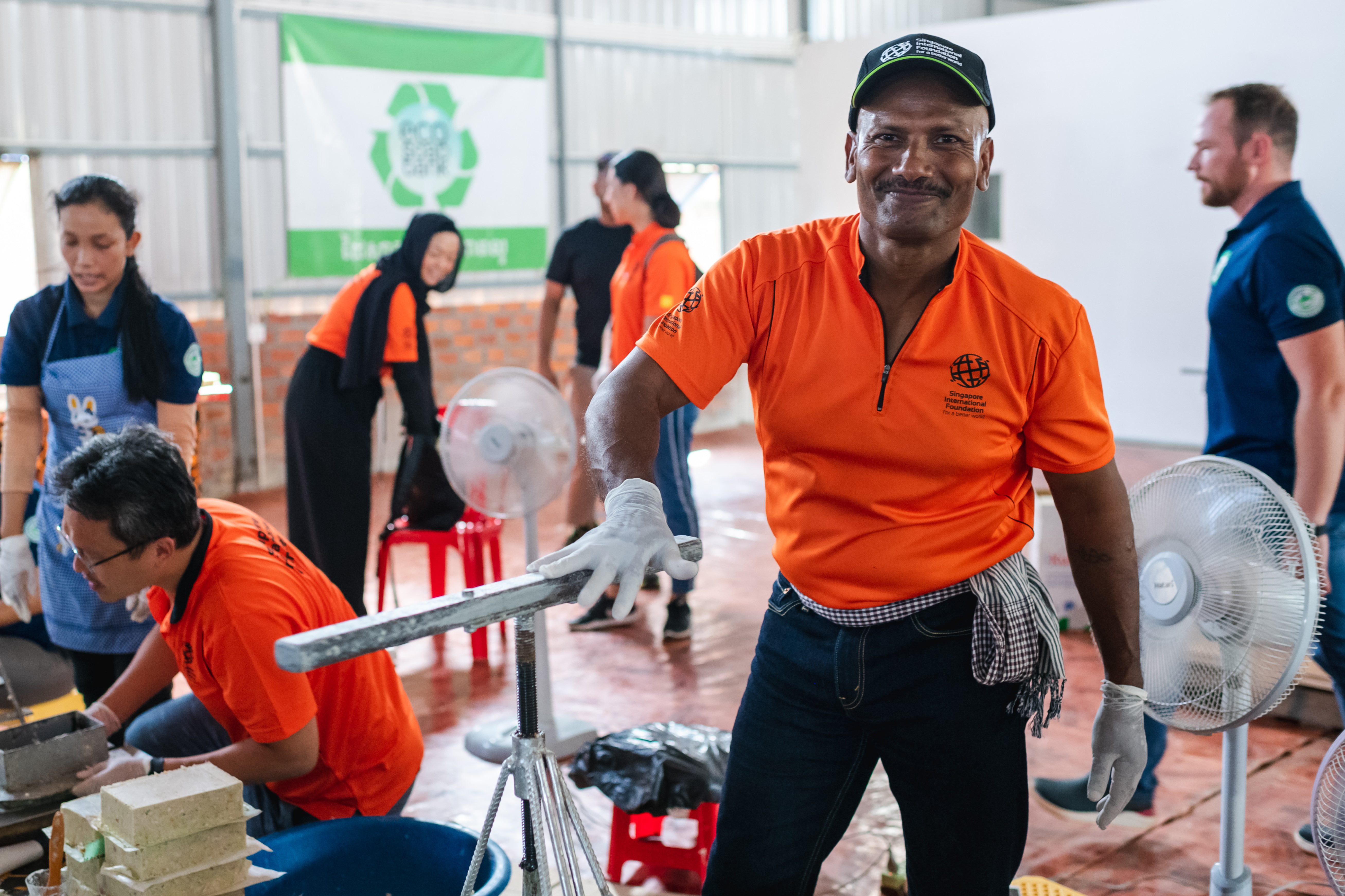 SIV Seluasundram Nagalingam (in orange, smiling) at a workshop to press soap scraps from hotels into new bars.