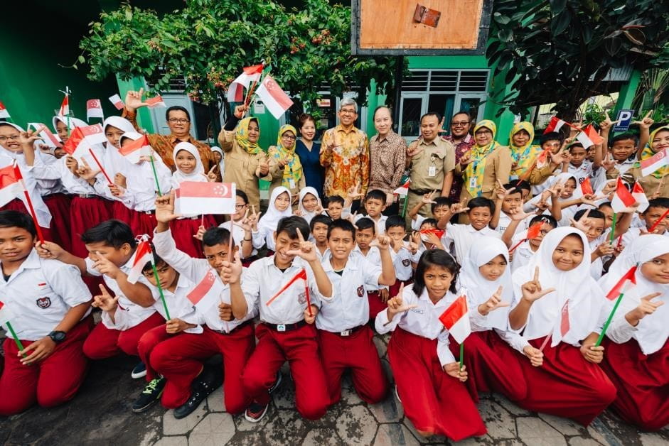 Dr Yaacob Ibrahim, Minister of Communications and Information (centre, in batik), gesturing an ‘L’ handsign symbolising “Salam Literasi”, or Literacy Greetings, promoting the spirit of learning and reading, together with Ms Jean Tan, Executive Director, SIF (in blue), Associate Professor Peter Pang, Governor, SIF (to the right of Minister), Mr Budi Wibowo, Head, BPAD DIY (back row, extreme left in batik), and students and staff of Timuran State Primary School.