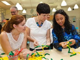 A student from the Little Arts Academy demonstrates how to weave a ketupat using ribbon.